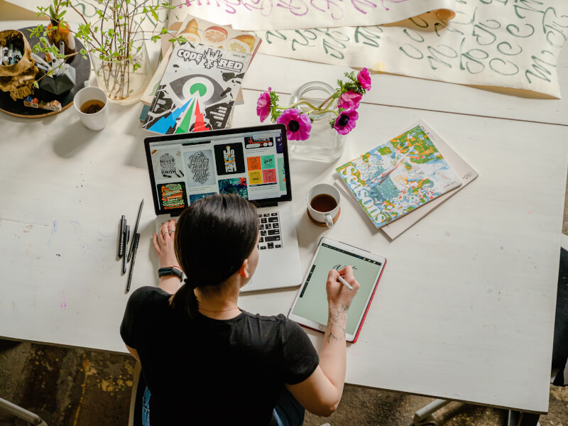 a person sits a table with a laptop and some craft equipment